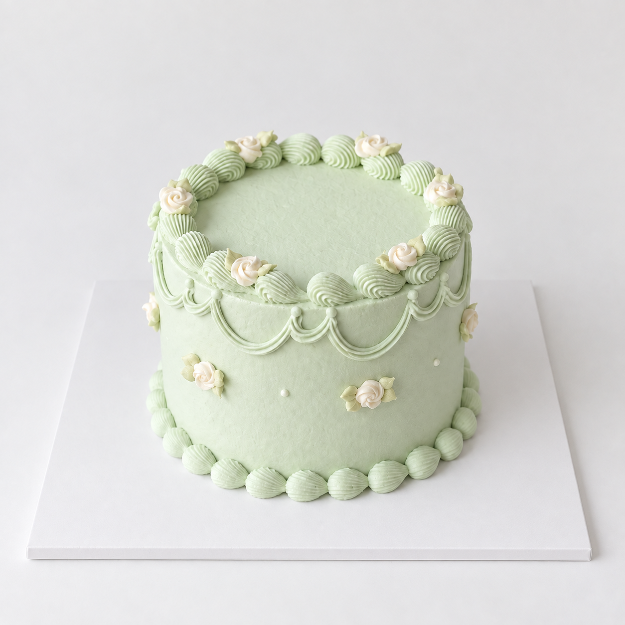 Round pastel green vintage rose cake with ivory roses, piped garlands and shell borders